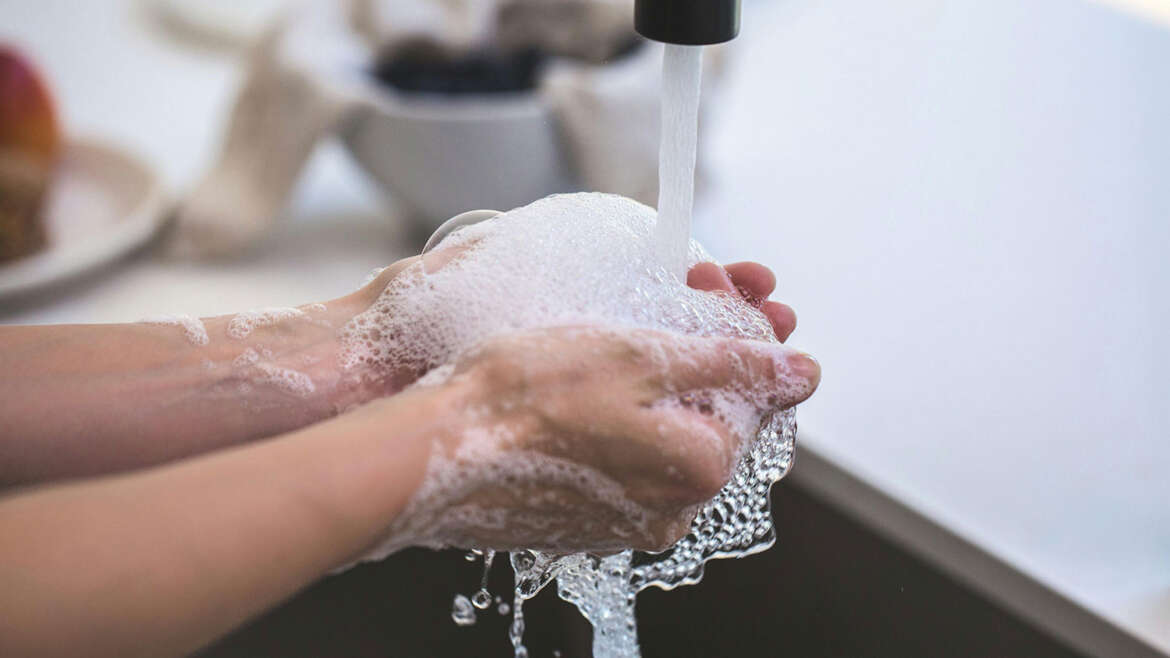 Mãos lavadas com sabão, com bactérias sendo eliminadas. Prevenção contra infecções.